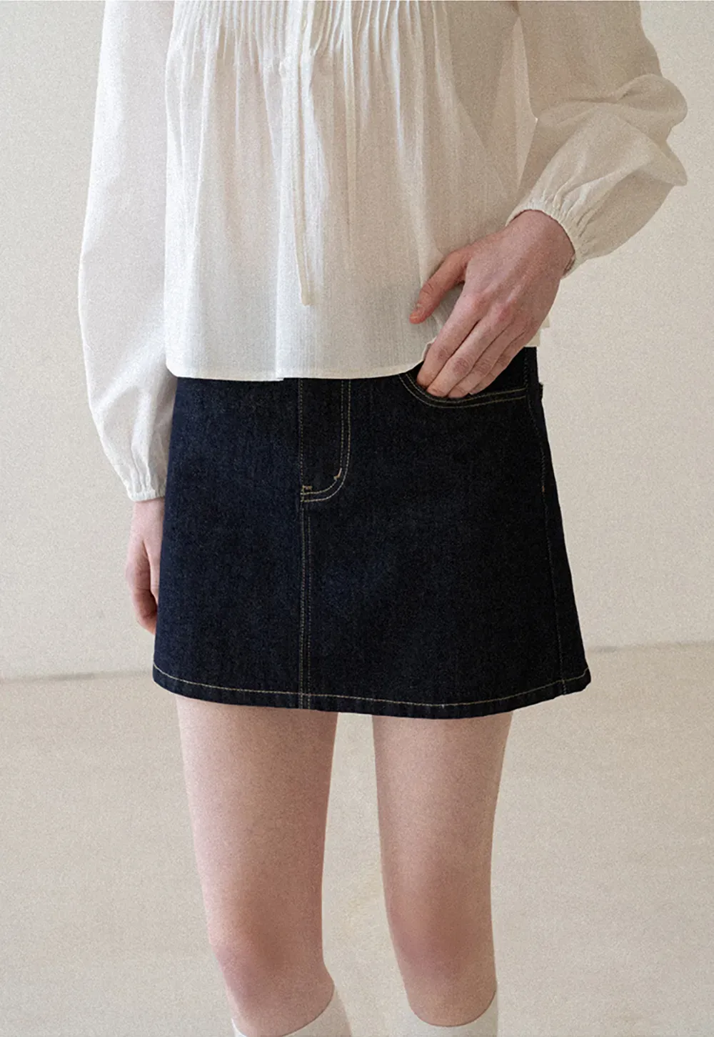 A-line denim skirt with front pocket design and adjustable waistband.