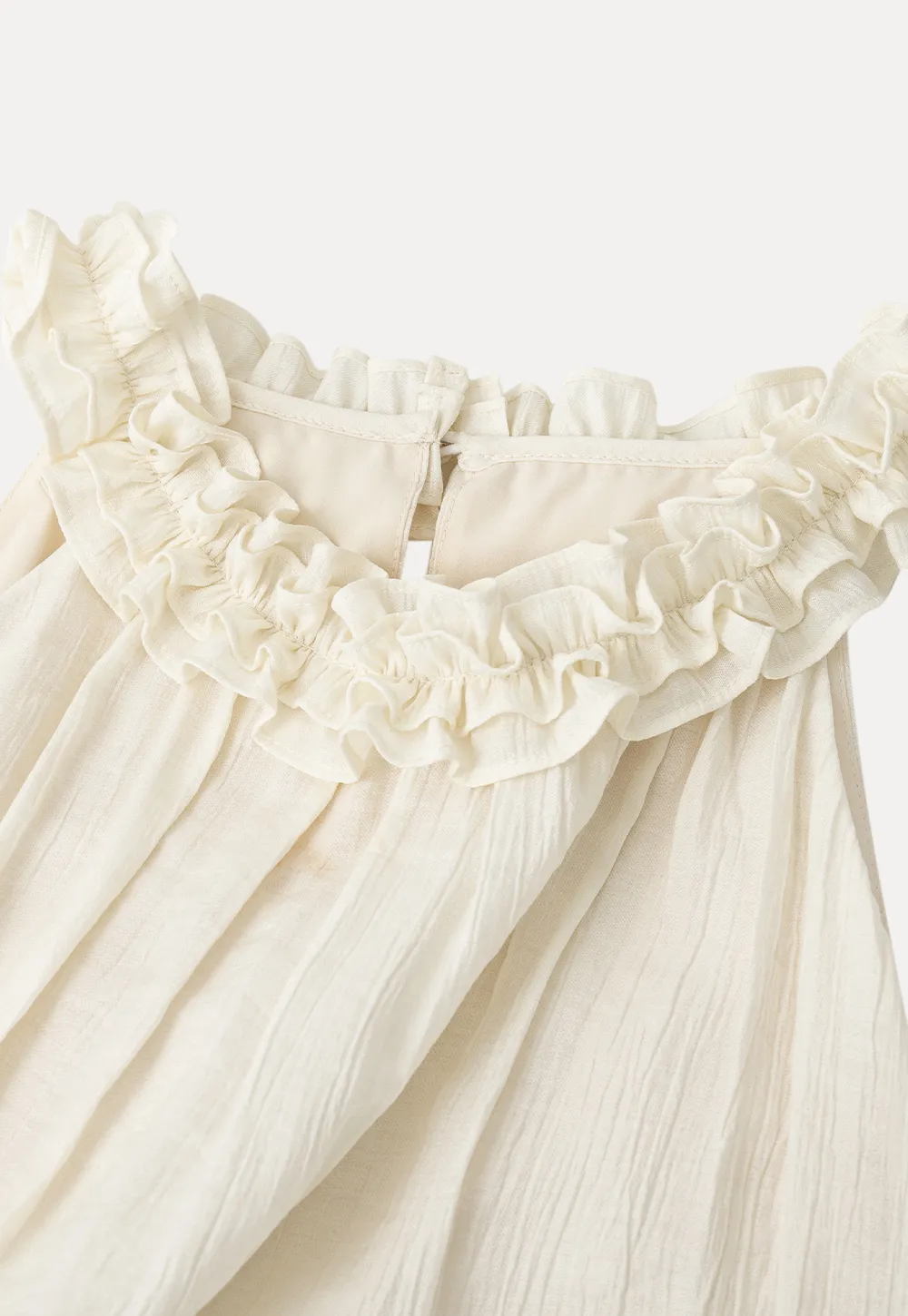 Sleeveless blouse with ruffled neckline and pleats