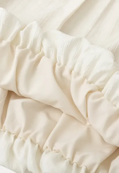 Sleeveless blouse with ruffled neckline and pleats