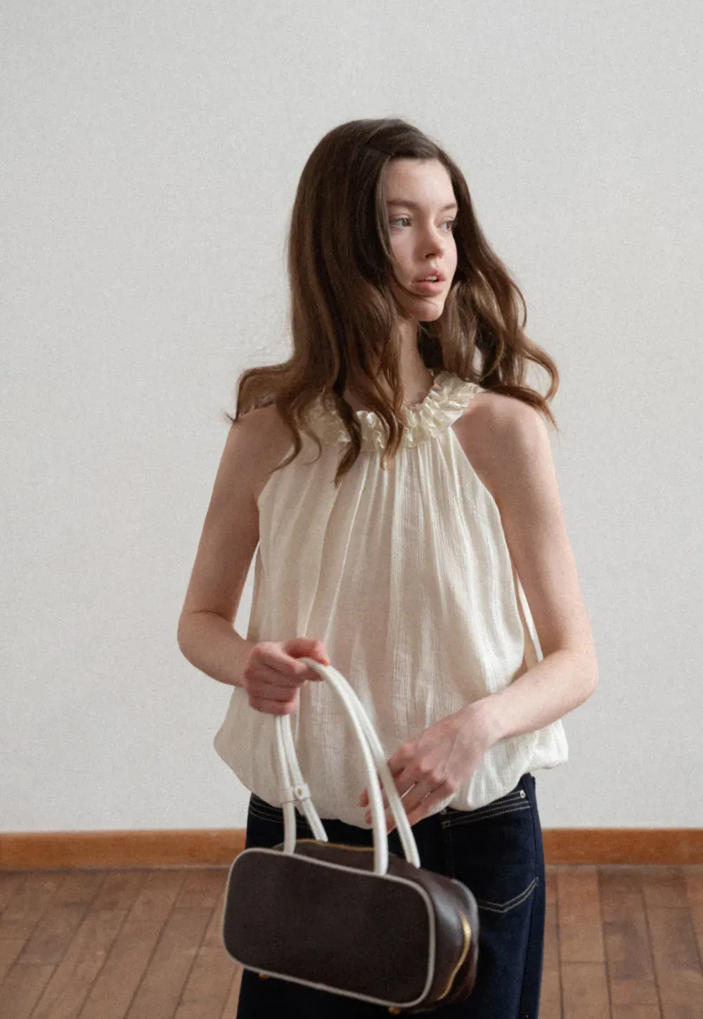 Sleeveless blouse with ruffled neckline and pleats