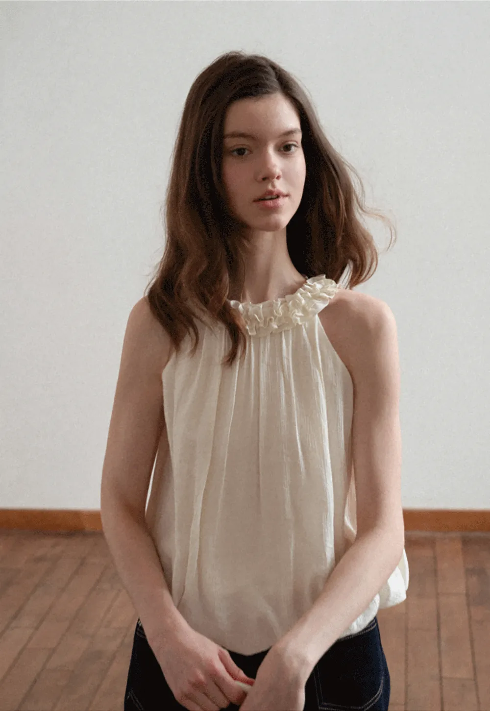 Sleeveless blouse with ruffled neckline and pleats