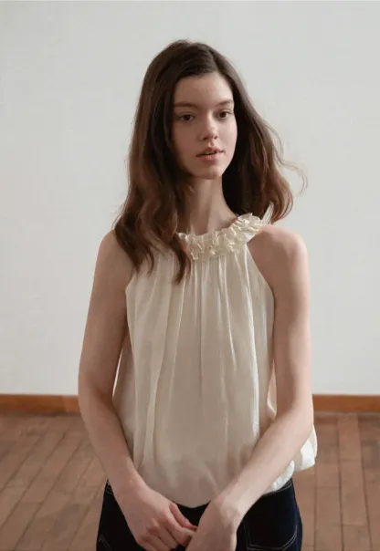 Sleeveless blouse with ruffled neckline and pleats