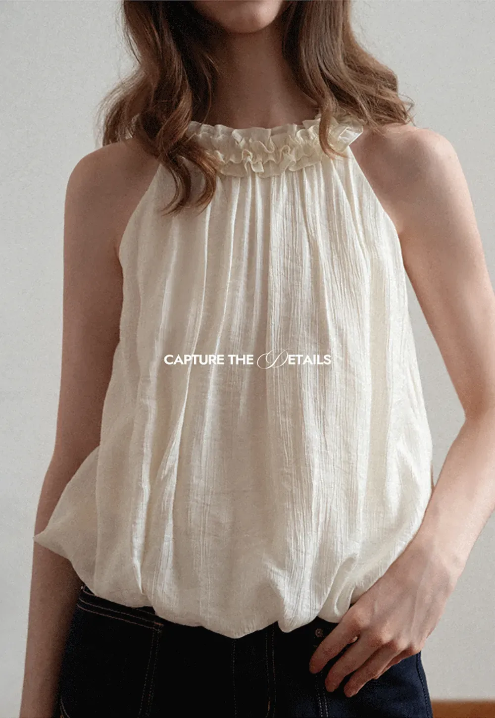 Sleeveless blouse with ruffled neckline and pleats