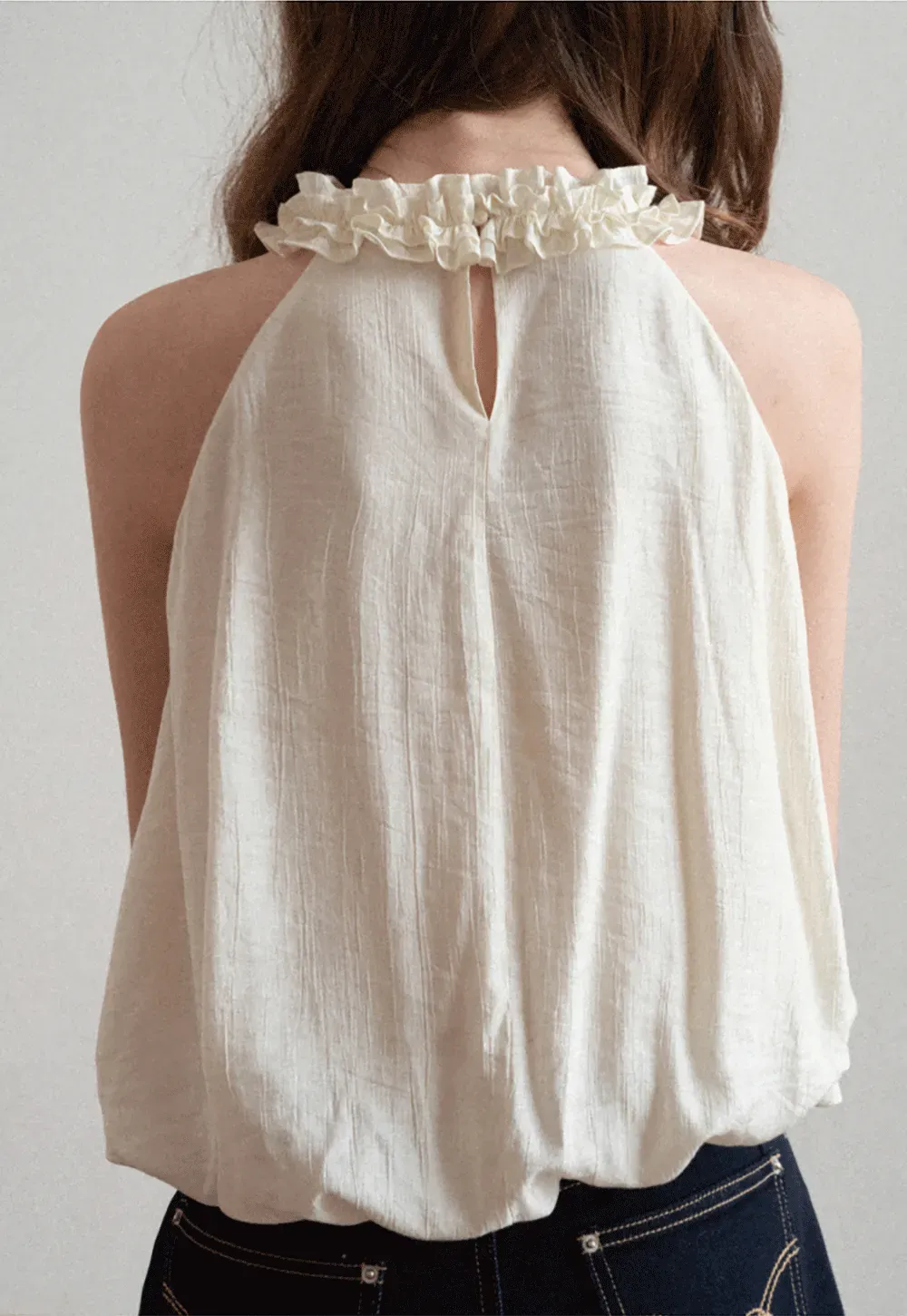 Sleeveless blouse with ruffled neckline and pleats