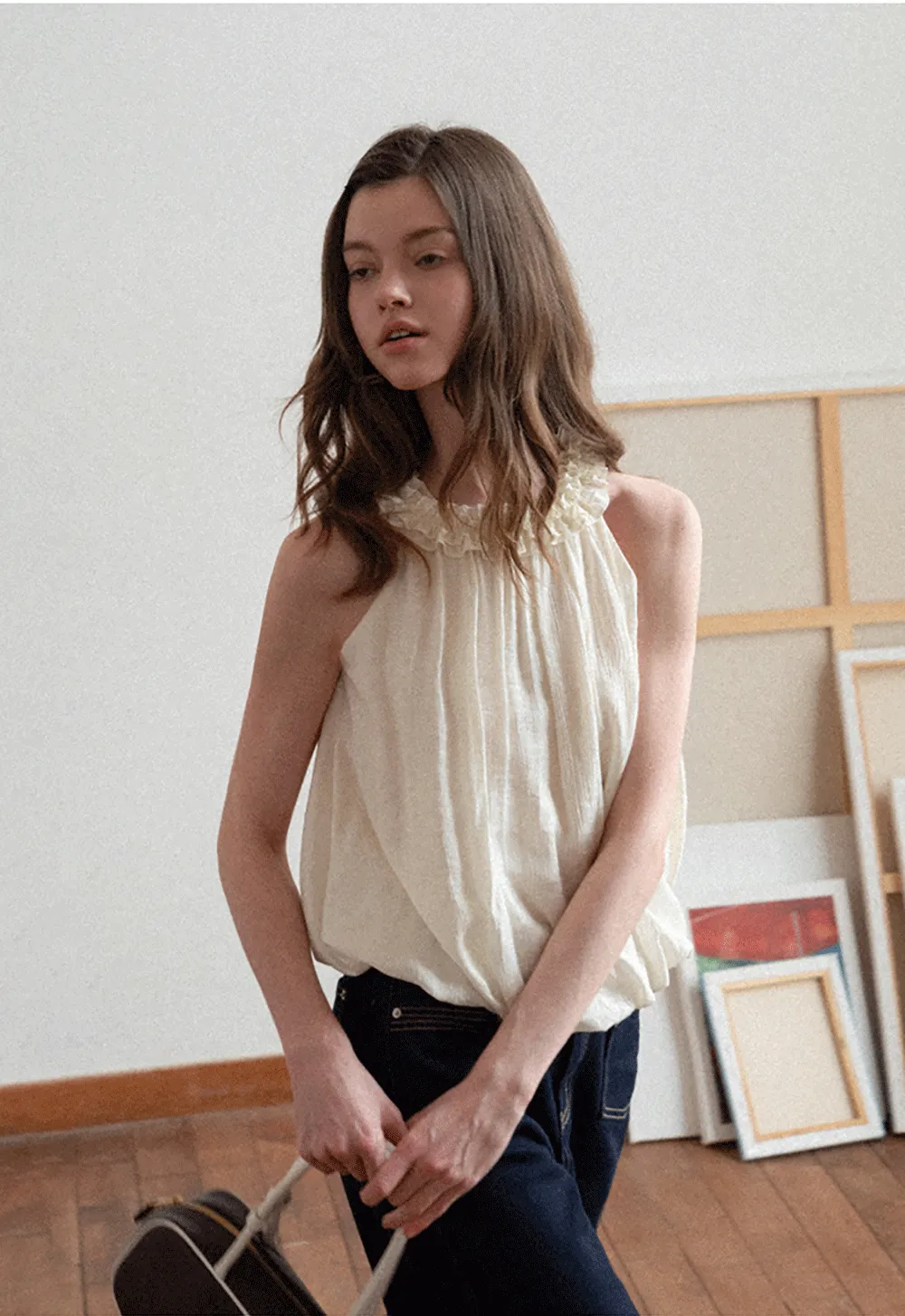 Sleeveless blouse with ruffled neckline and pleats