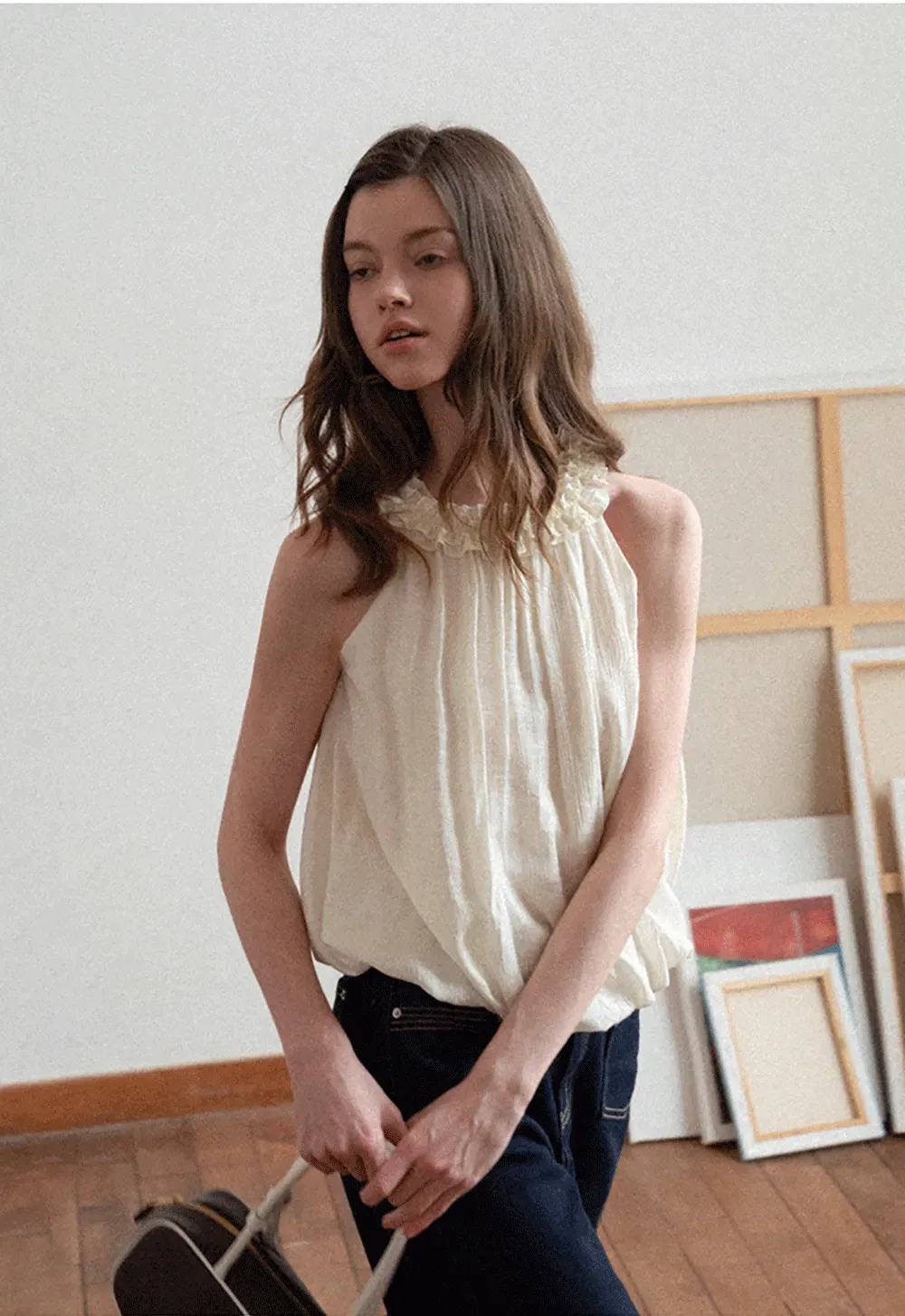 Sleeveless blouse with ruffled neckline and pleats