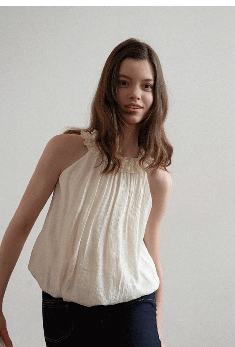 Sleeveless blouse with ruffled neckline and pleats