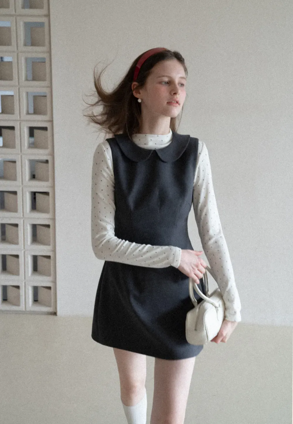 Elegant sleeveless dress with collar layered over polka dot top