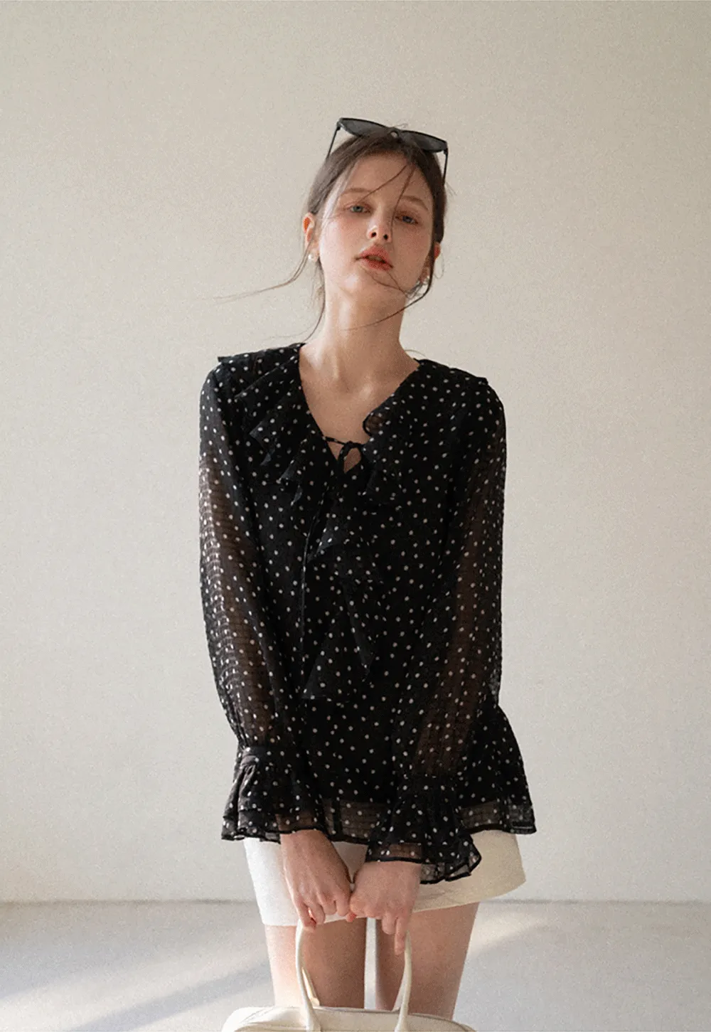 Sheer polka dot blouse with ruffled neckline and long sleeves