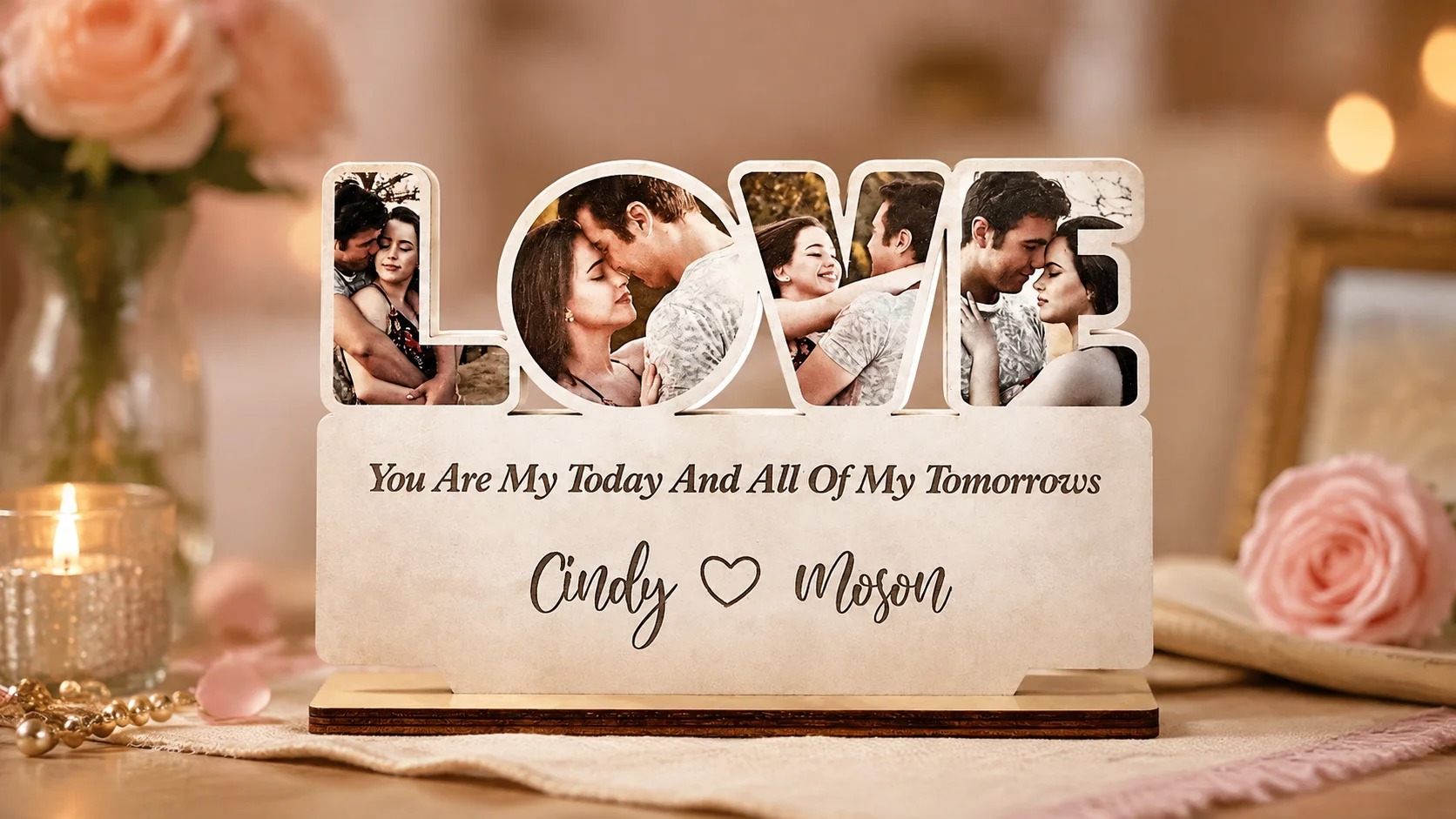 A wooden sign spelling LOVE with four couple photos set into the letters, standing on a wooden base, engraved with a message and two names below