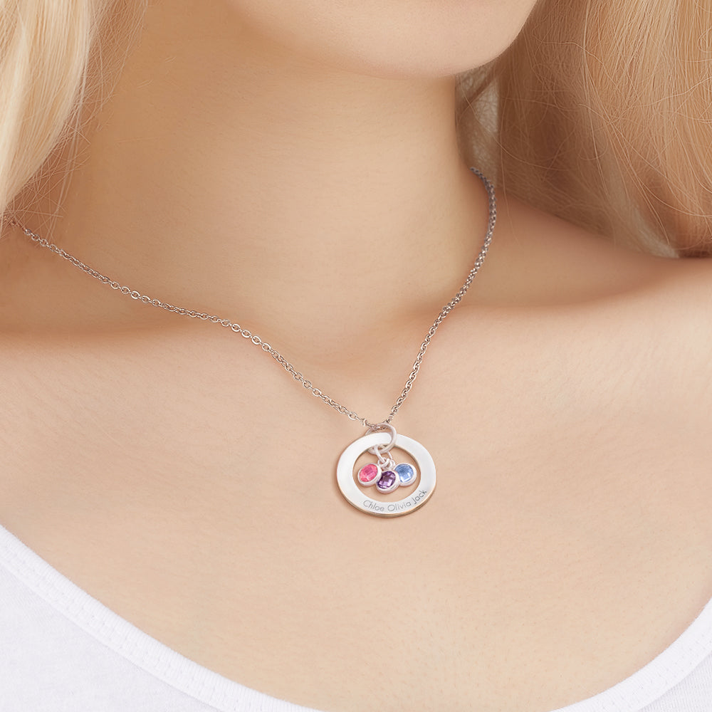 A personalized birthstone necklace displayed on a pink background.