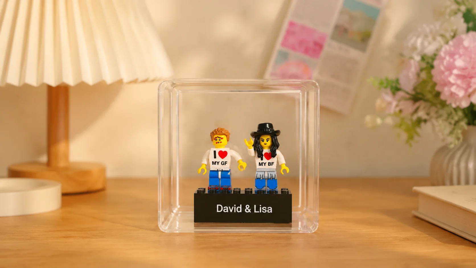 Two custom minifigs printed with "I love MY GF" and "I love MY BF" shirts, standing on a base engraved "David & Lisa" inside a clear display box