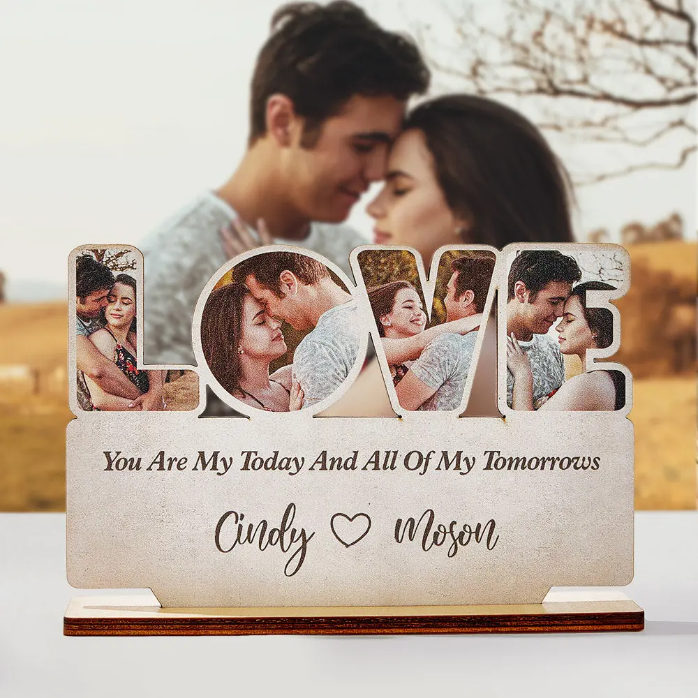 A close-up of the LOVE photo plaque with a large blurred romantic couple photo in the background