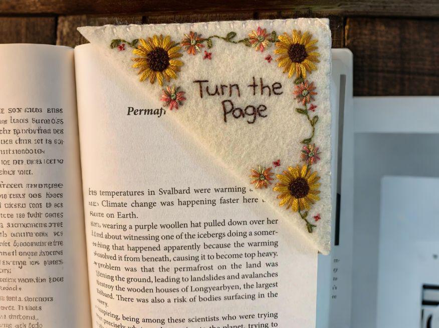 The felt sunflower bookmark tucked over the corner of an open book page