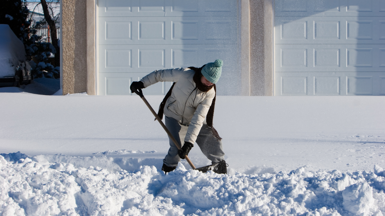 Shoveling snow from gravel driveway.