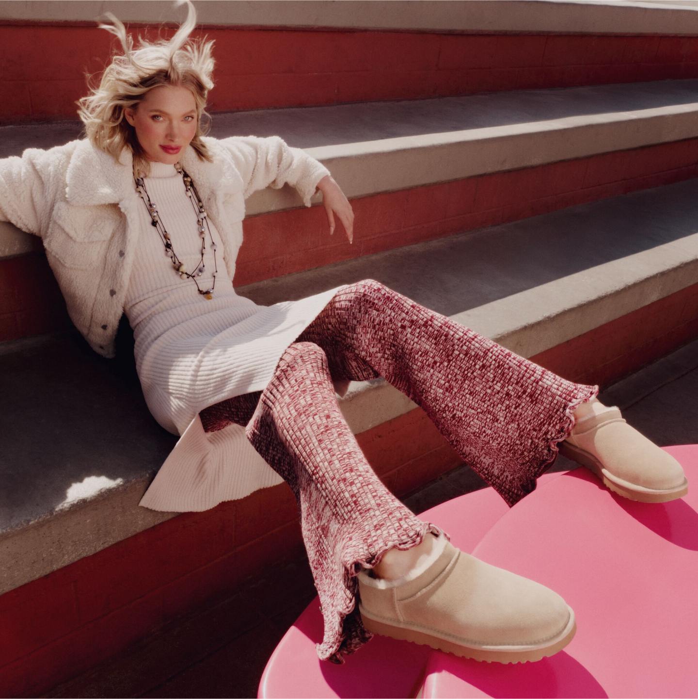 A model poses on colourful steps, dressed in the Frankie Short Trucker Jacket over a  dress with  pants, and Classic Micro.
