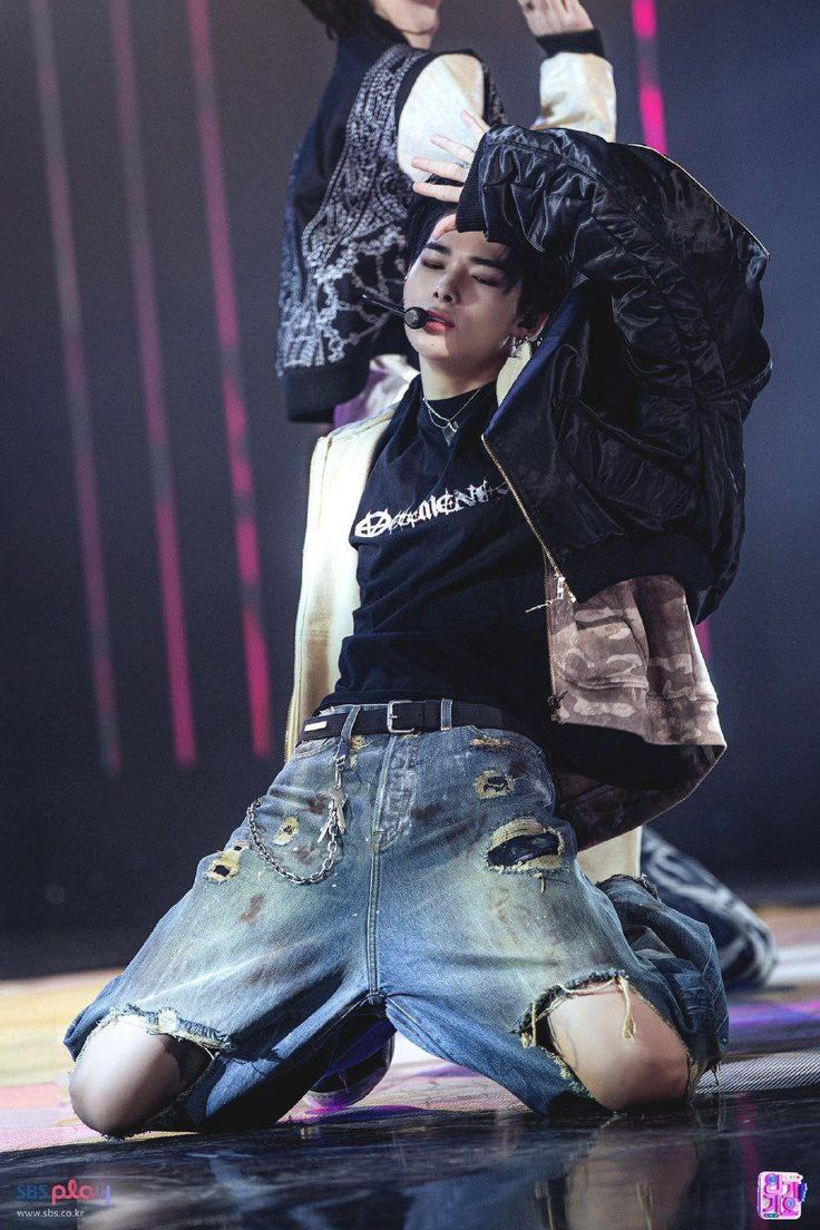 This may contain: two young men sitting on the ground with their arms in the air and one man standing behind them