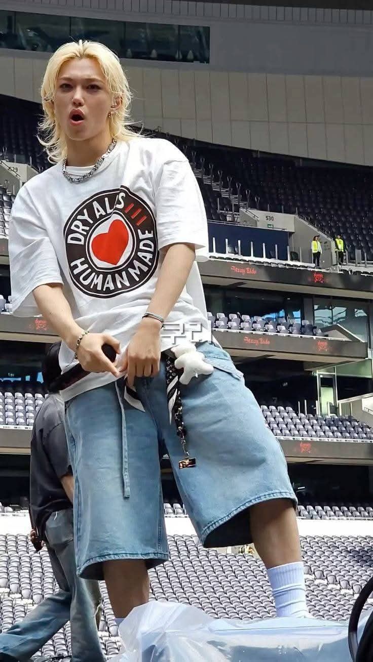 This may contain: a young man with blonde hair is sitting on a bench in front of an empty bleachers