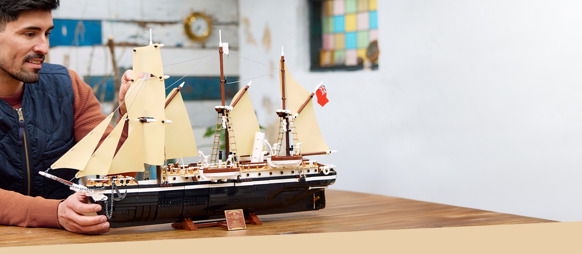 レゴアイコン エンデュアランス号のセットのライフスタイル画像。男性が、ディスプレイ用のスタンドに置かれた組み立てモデルを手に取っています。