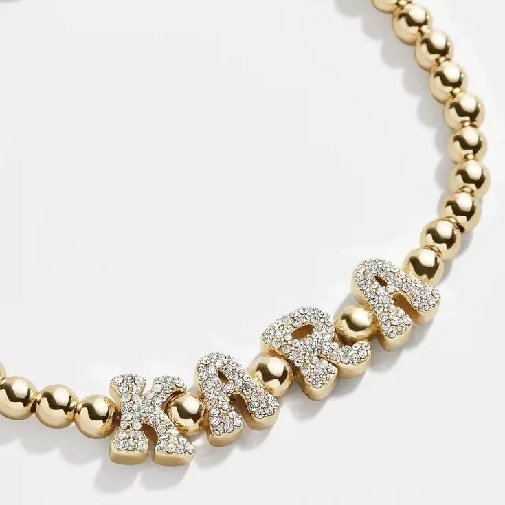 Close-up showing the durable stretch cord and 5mm gold beads of the custom letter bracelet