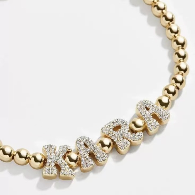 Close-up showing the durable stretch cord and 5mm gold beads of the custom letter bracelet