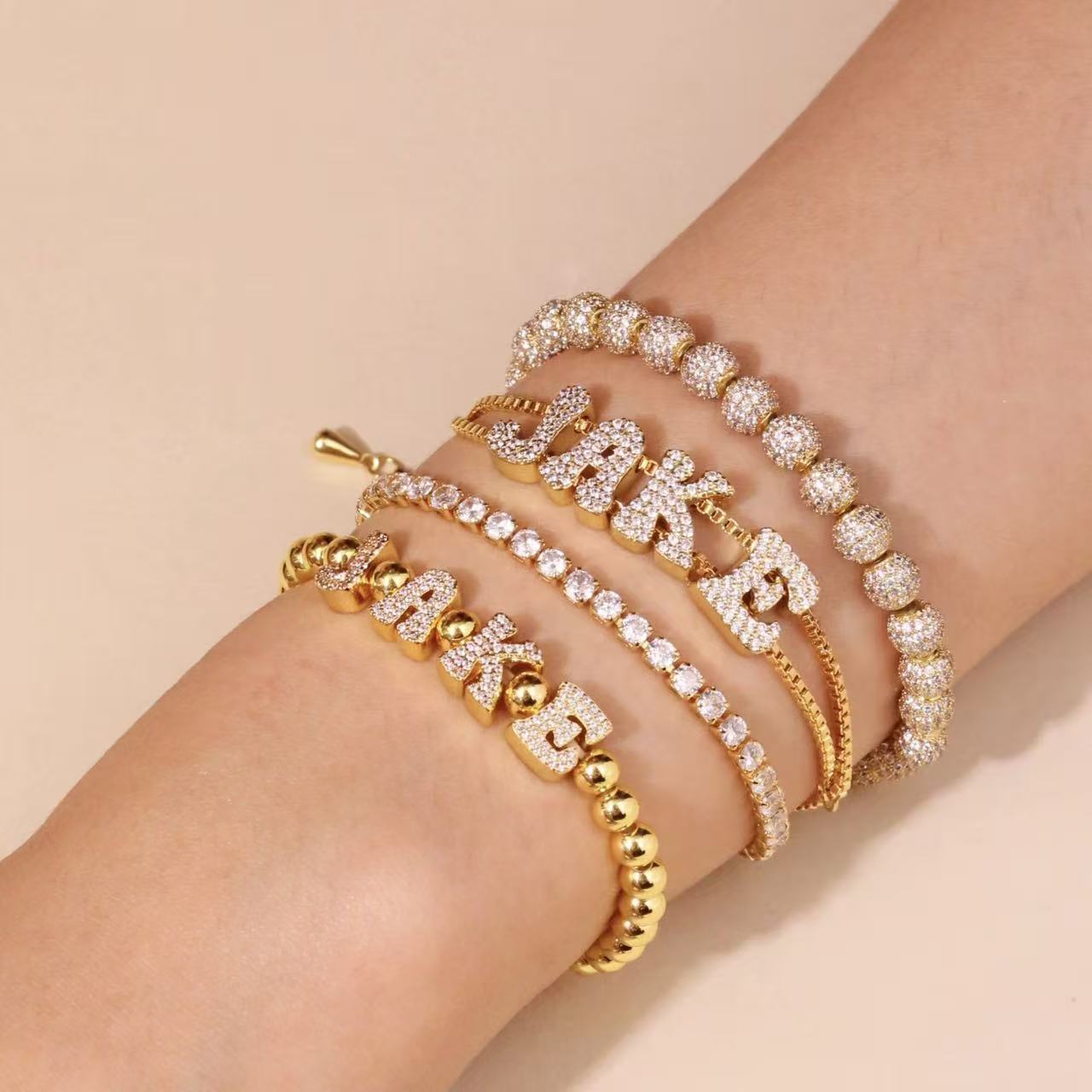 Model wearing a personalized gold bead stretch bracelet with cubic zirconia nameplate on the wrist