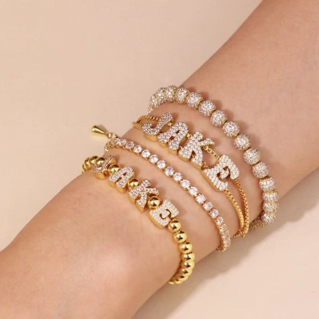 Model wearing a personalized gold bead stretch bracelet with cubic zirconia nameplate on the wrist