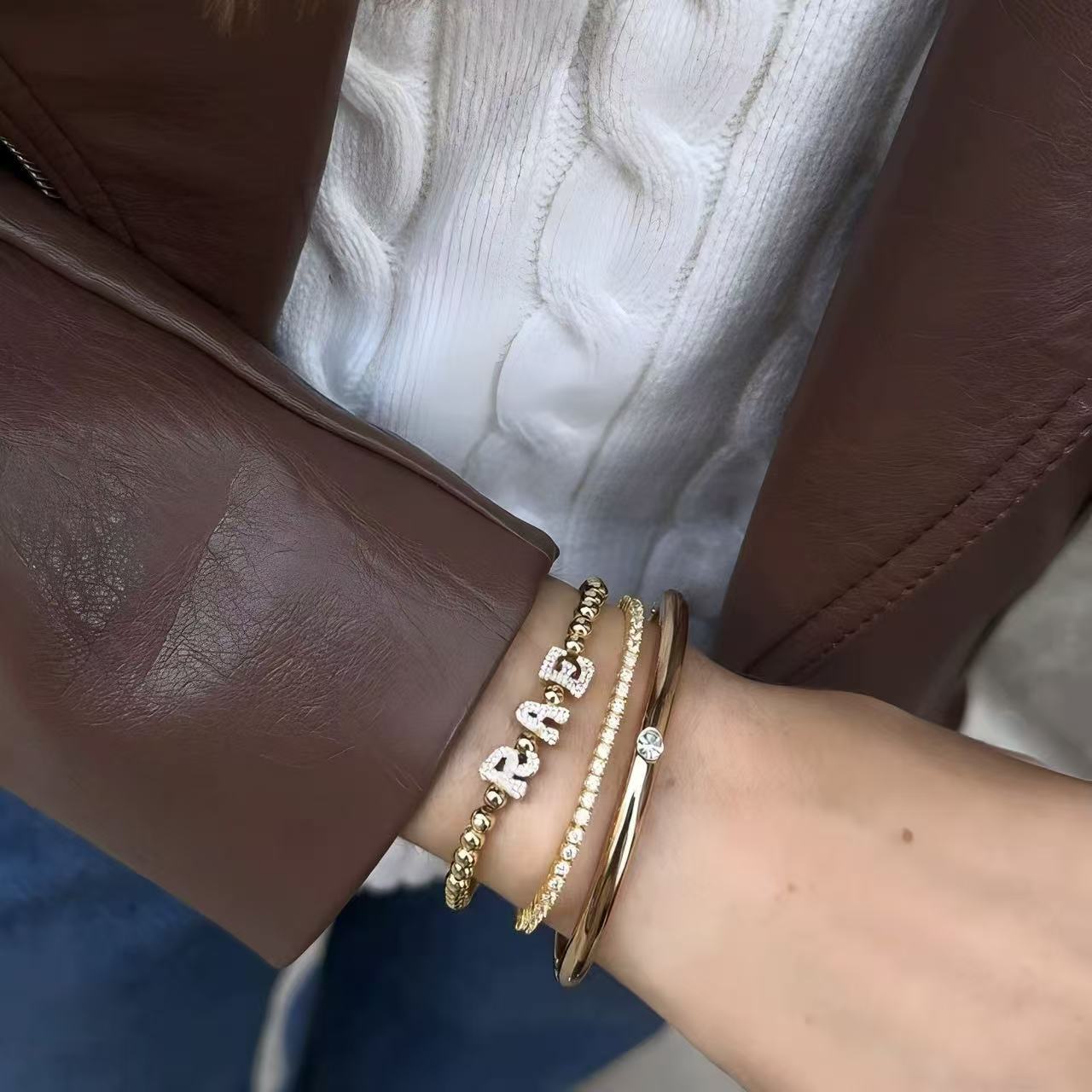 Model wearing a personalized gold bead stretch bracelet with cubic zirconia nameplate on the wrist