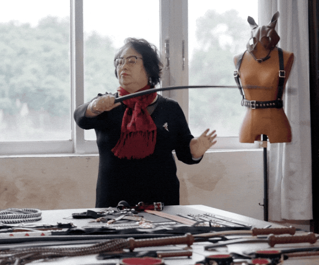 Lisa is inspecting the quality of a handcrafted BDSM whip. The whip has the perfect balance of firmness and flexibility, with soft leather that provides a secure grip and is not easy to slip from the hand
