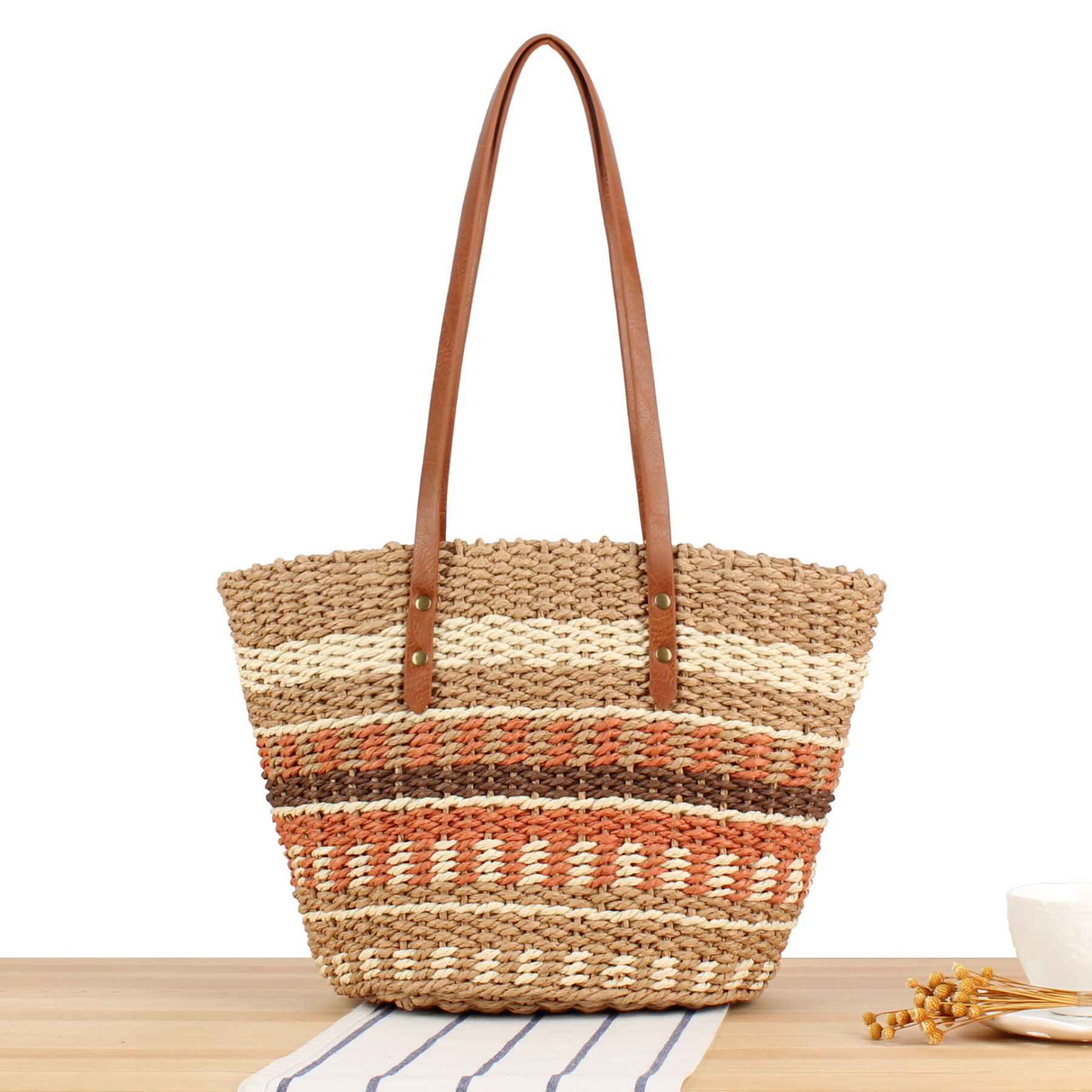 Boho handmade straw tote bag with leather handles displayed against a neutral background.
