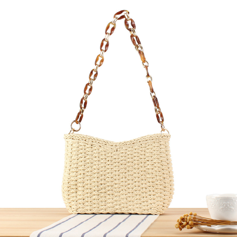 Small handmade straw pocketbook crossbody bag with chain strap, displayed against a neutral background.