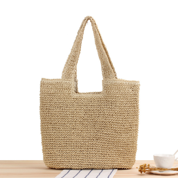 Oversized handwoven straw beach tote bag with top handles, displayed against a neutral background.