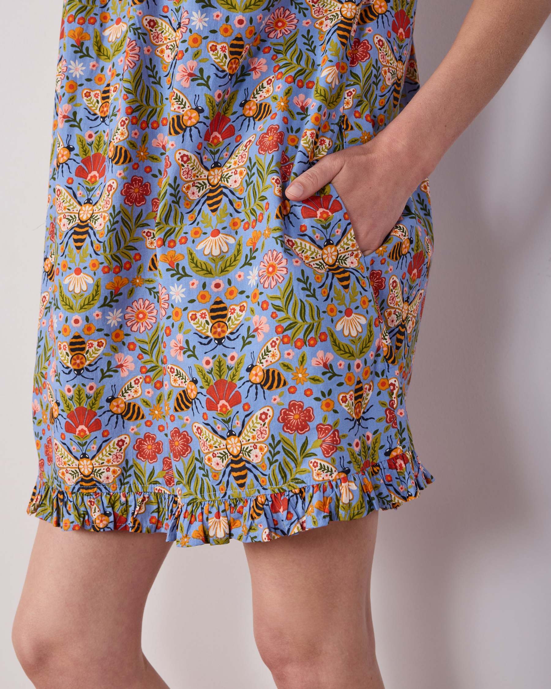 Close-up of the blue Bee Tapestry nightgown’s bee-and-floral print, side pocket, and ruffled hem.