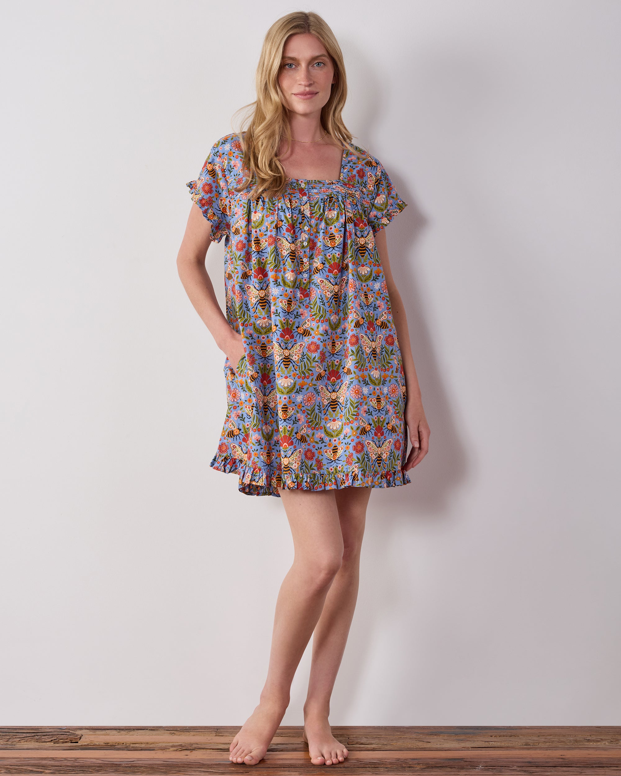 Model wearing the blue Bee Tapestry pintuck nightgown, shown from the front with short sleeves and a ruffled hem.