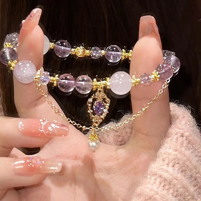 Amethyst bracelet with purple and clear beads, gold accents, held in hand, perfect gift for her.