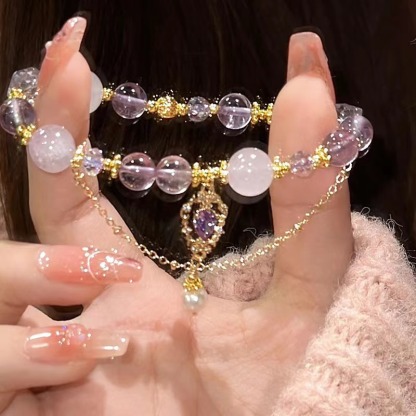 Amethyst bracelet with purple and clear beads, gold accents, held in hand, perfect gift for her.