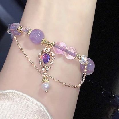 Amethyst bracelet with purple and clear beads, gold accents, held in hand, perfect gift for her.