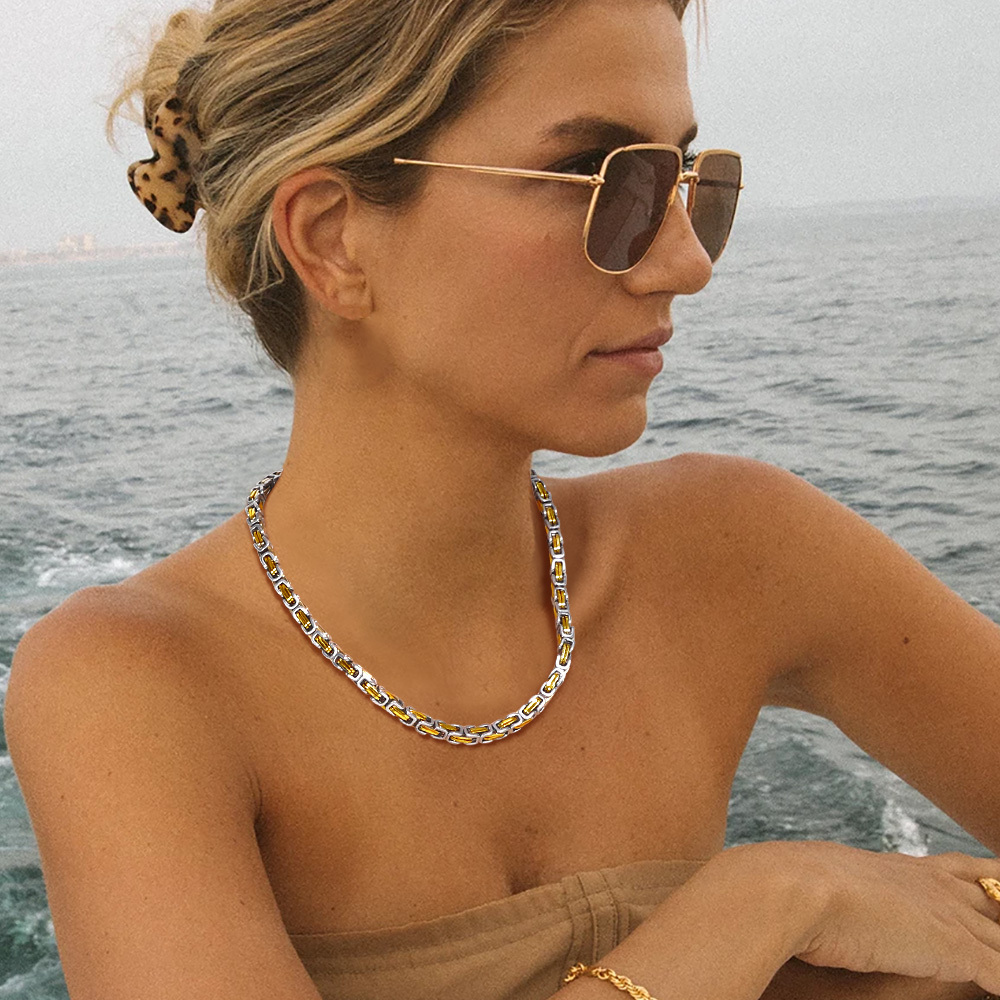 Female model wearing two-tone square Byzantine chain necklace outdoors by the sea