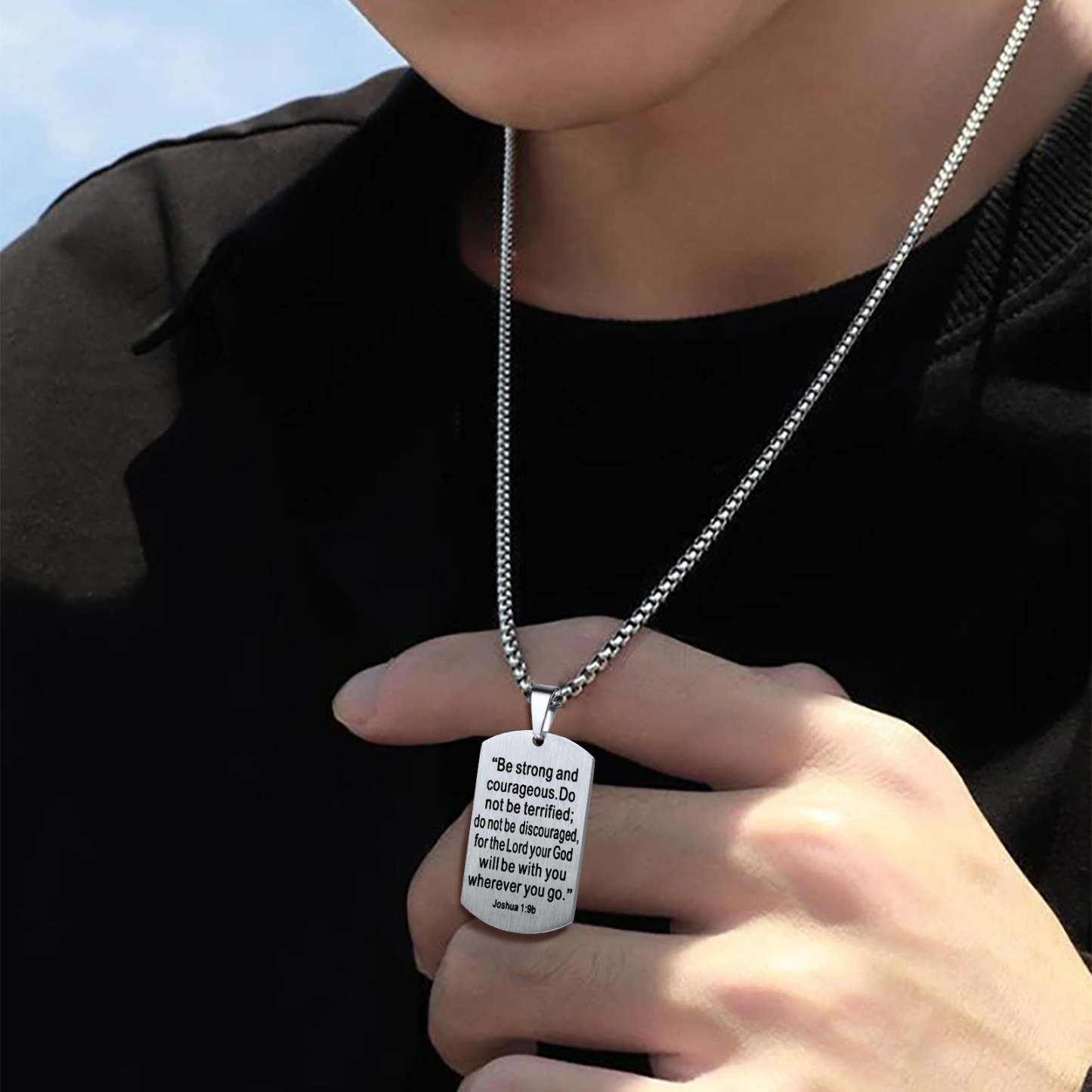 Bible verse dog tag pendant held in hand with silver chain