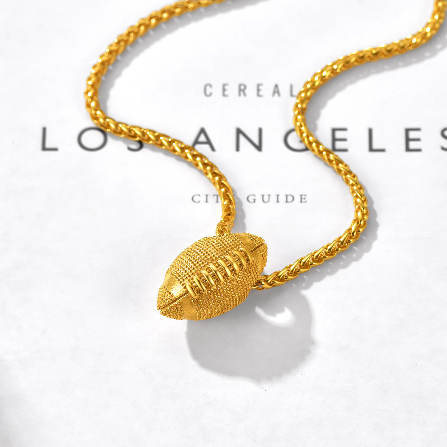 Gold football pendant necklace styled on magazine flat lay