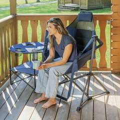 Woman sitting on swing chair on sunny cabin's deck.
