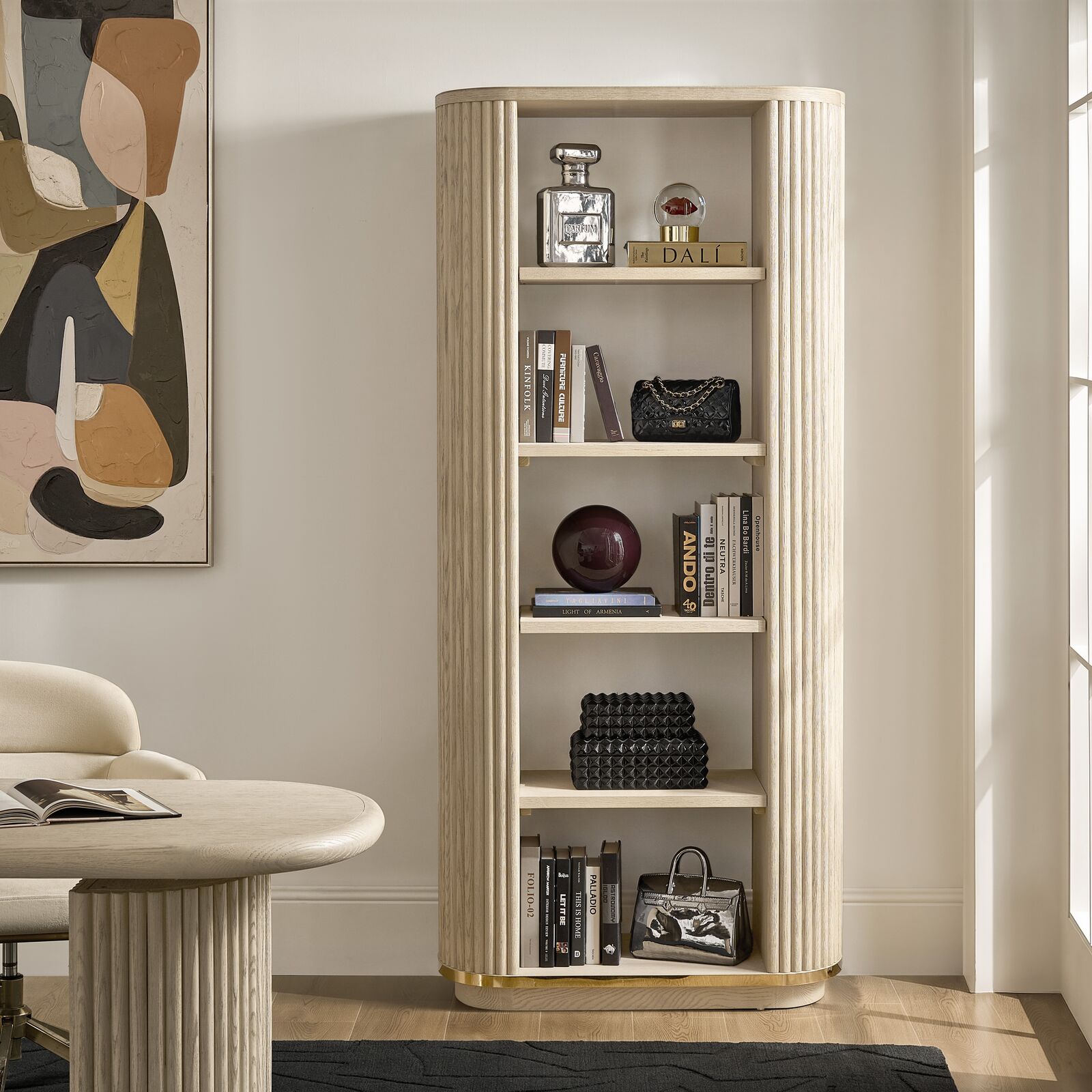 Modern tall fluted cream bookcase with curved arched shelving displaying books, art objects, and decorative accents.