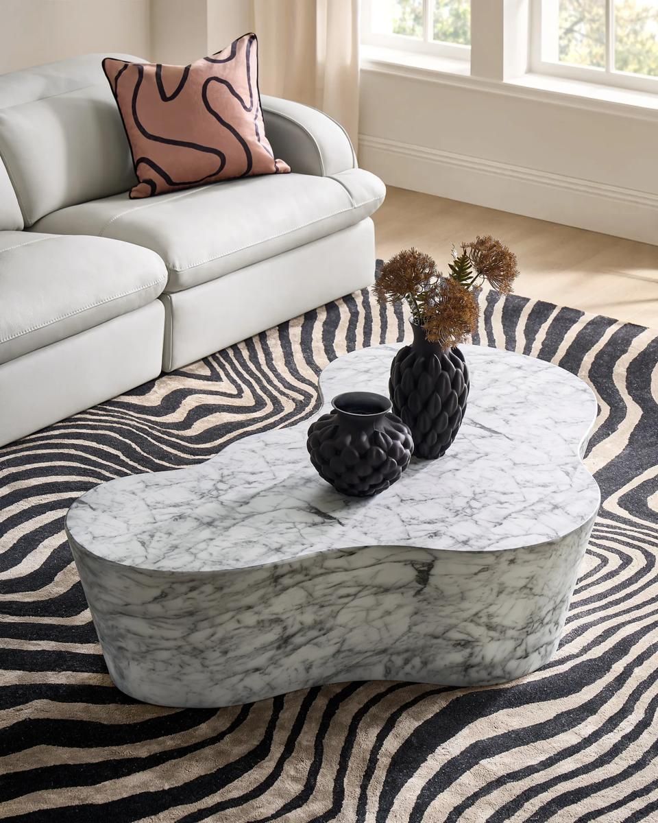 How to style a coffee table with a tray, book stack, candle, and tall vase in a modern glam living room
