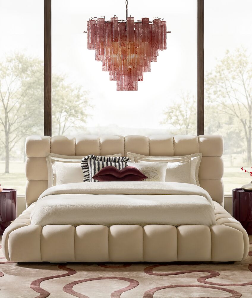 Modern luxury bedroom featuring an off-white channel tufted upholstered platform bed paired with a tiered pink glass rod chandelier.