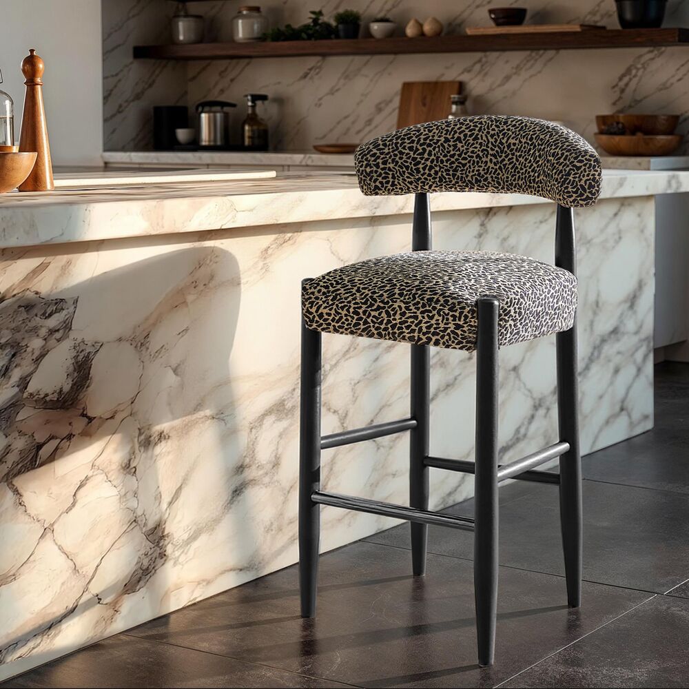 Modern barstool upholstered in textured leopard-print fabric with sleek black legs set against a white marble kitchen island.