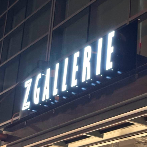 Illuminated white exterior storefront sign displaying the Z Gallerie brand name on a building facade at night.