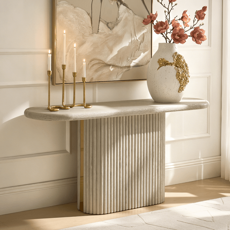 Modern fluted console table topped with gold candelabra and a textured vase with gold floral details.