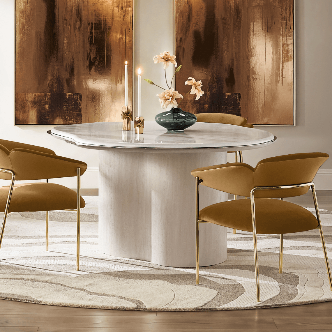 Modern round white pedestal dining table styled with yellow ochre dining chairs, gold taper candleholders, and amber abstract canvas art.