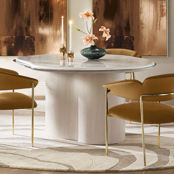 Modern white pedestal dining table surrounded by ochre velvet dining chairs with brass legs, set over a wavy patterned area rug.