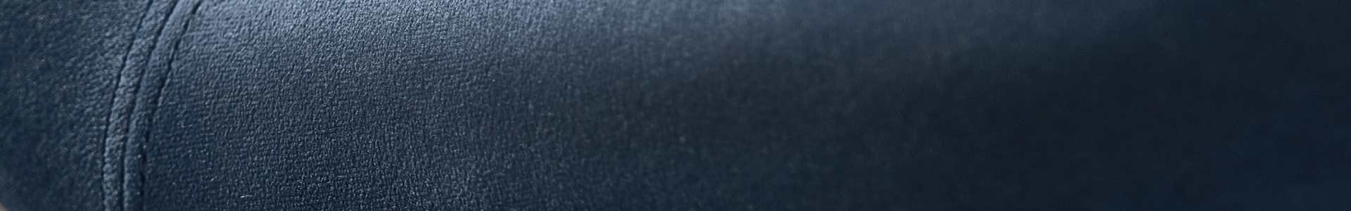 Close-up texture of deep navy blue velvet upholstery with detailed stitching.